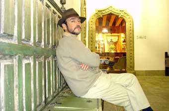 Individuo sentado sobre un banco y oculto bajo el sombrero de Javier Puebla y barba.